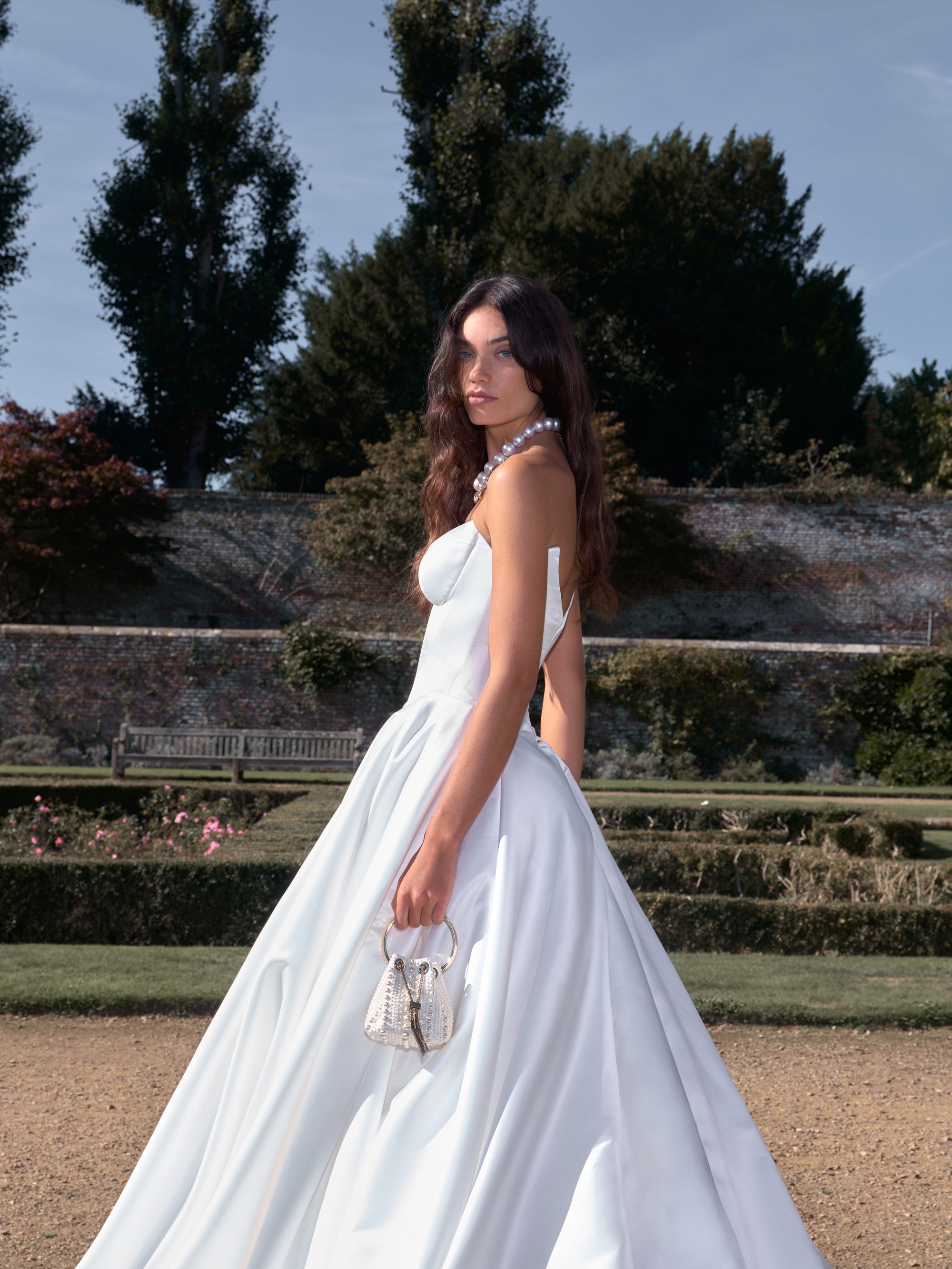 Woman in a white dress standing in an outdoor garden setting