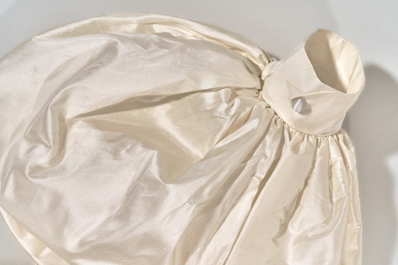 Beige drawstring bag with a button on a light gray background