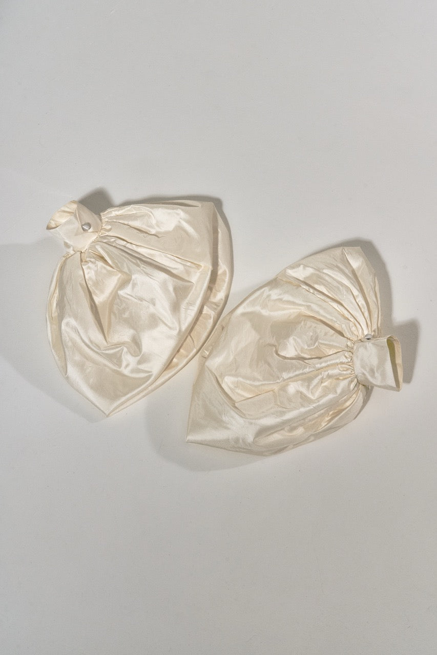 Pair of cream-colored earrings on a light gray background