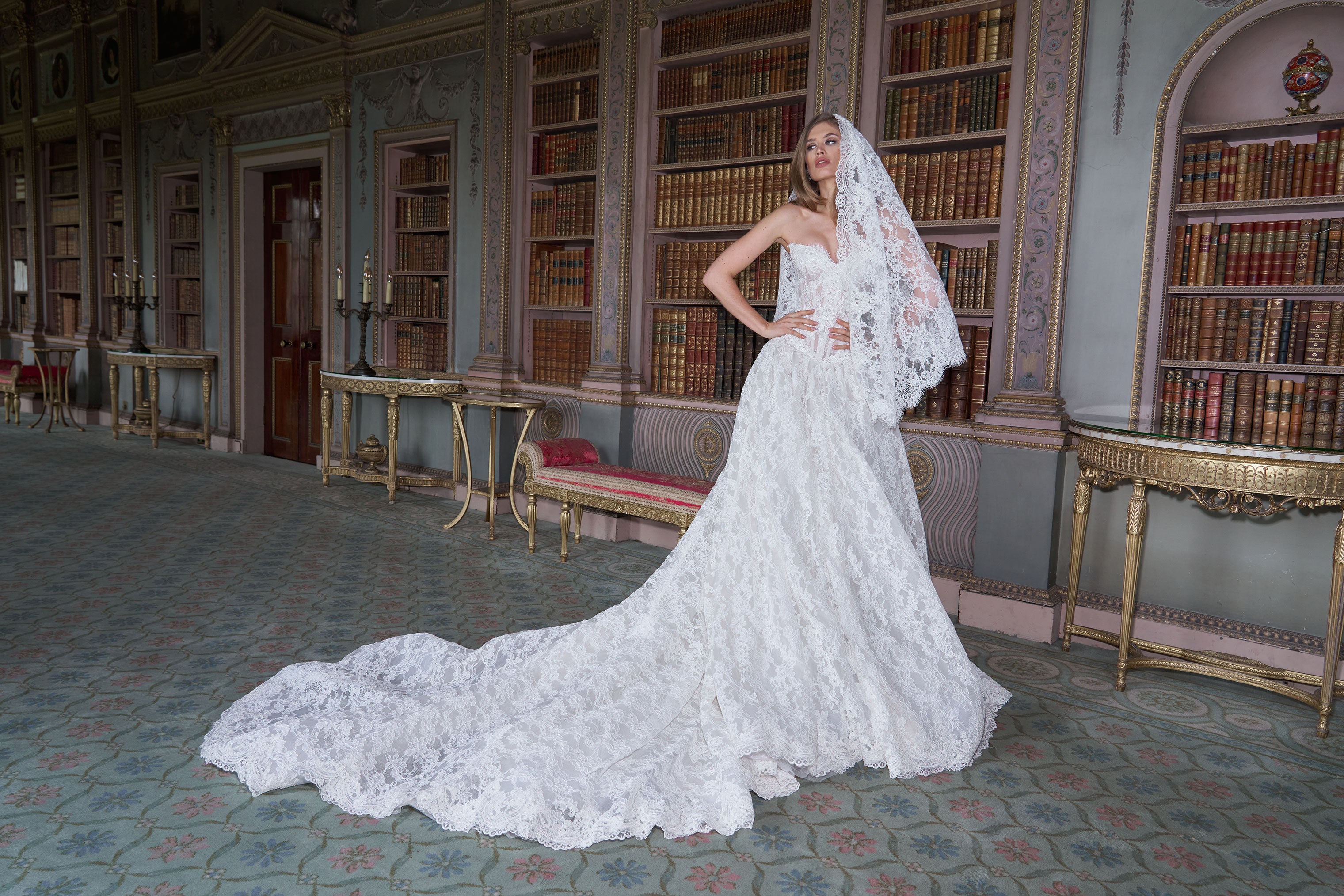 Woman in a white wedding dress standing in a grand room with bookshelves.