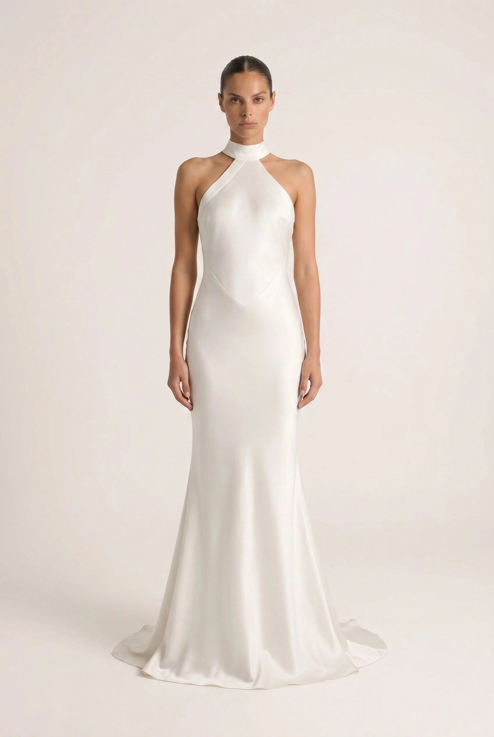 Woman wearing a white halter neck gown on a plain background