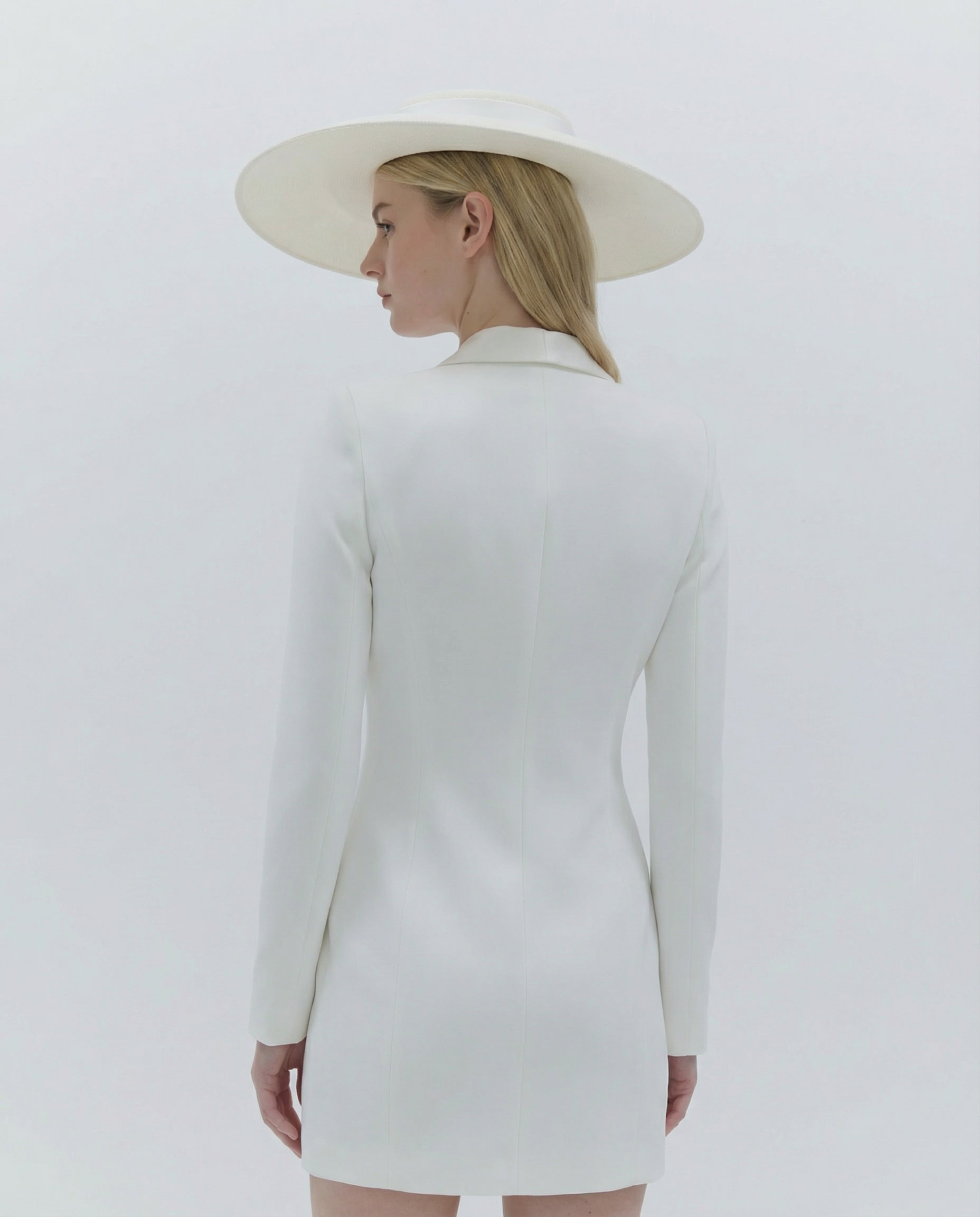 Person wearing a white dress and hat against a light gray background