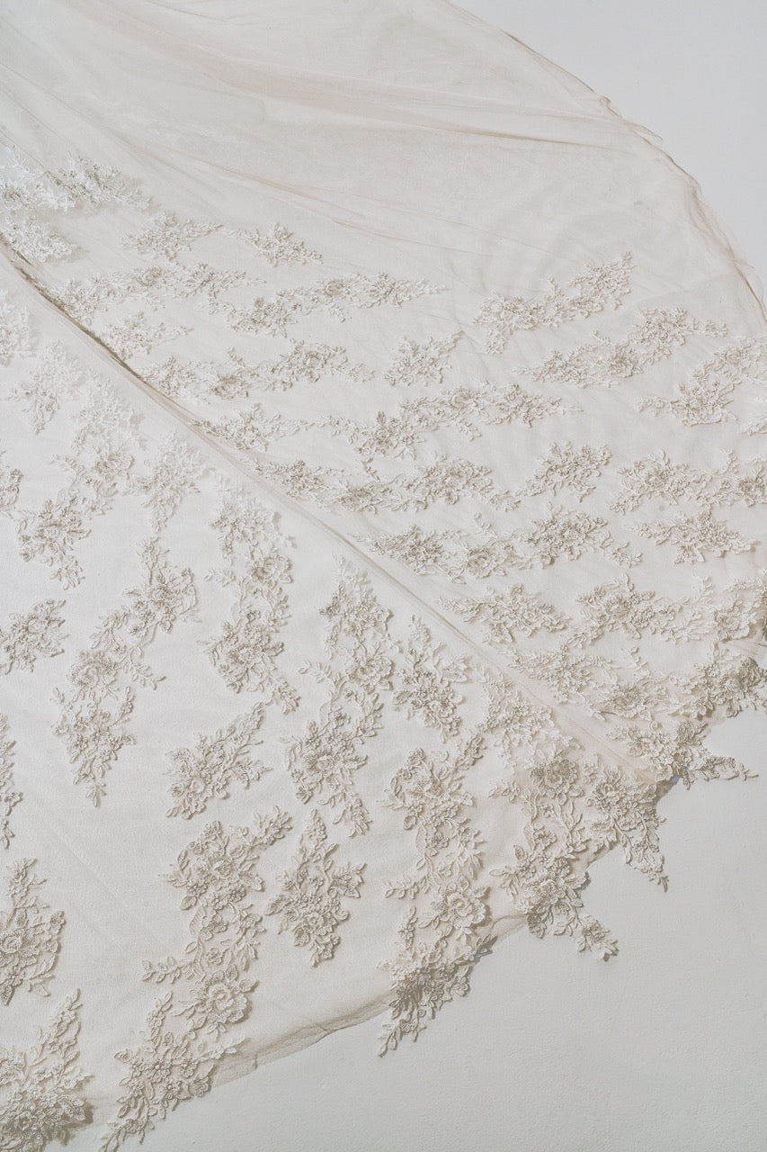 Close-up of a white lace garment with intricate detailing on a light background