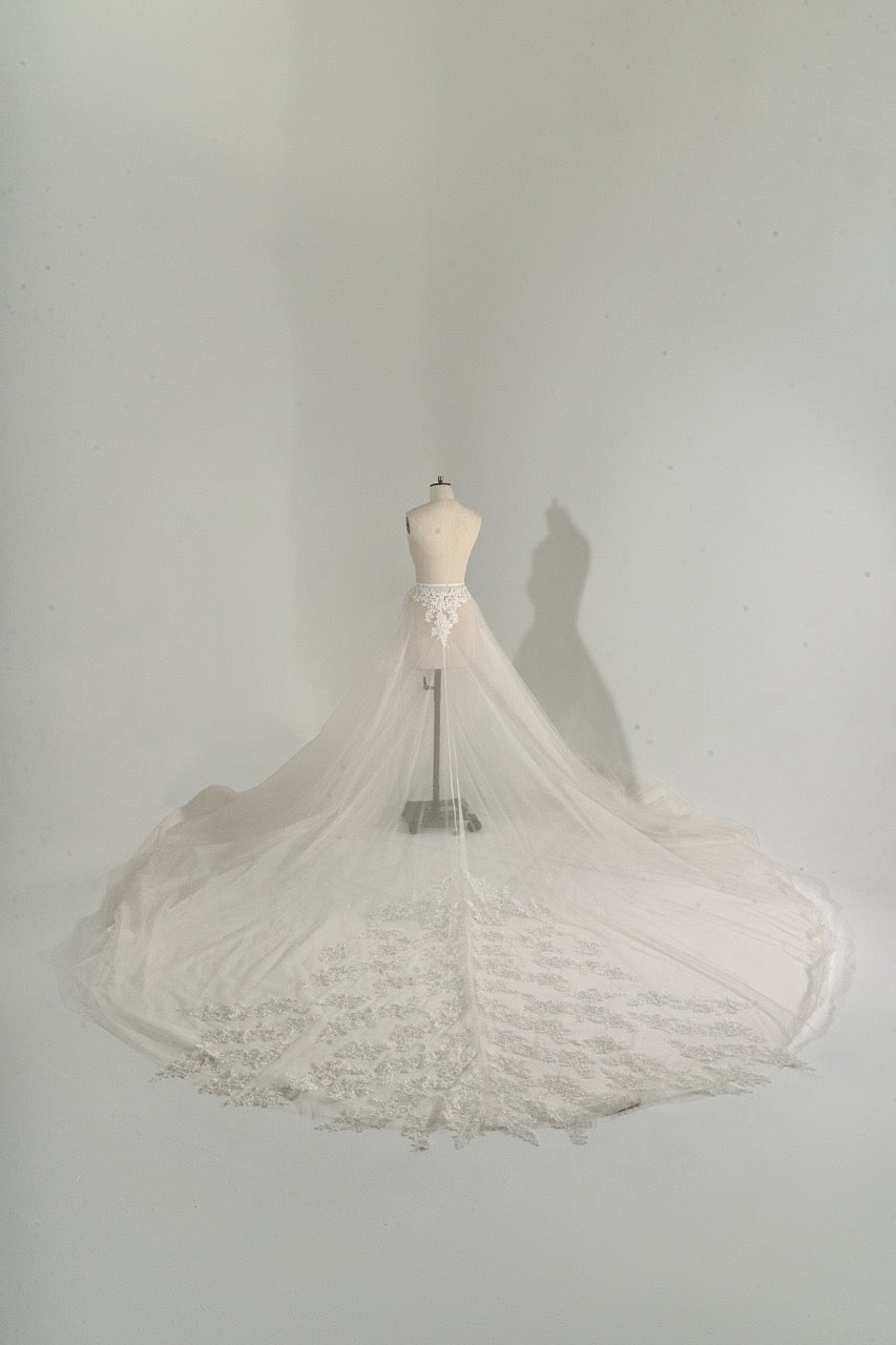 White lace wedding dress on a mannequin against a plain white background