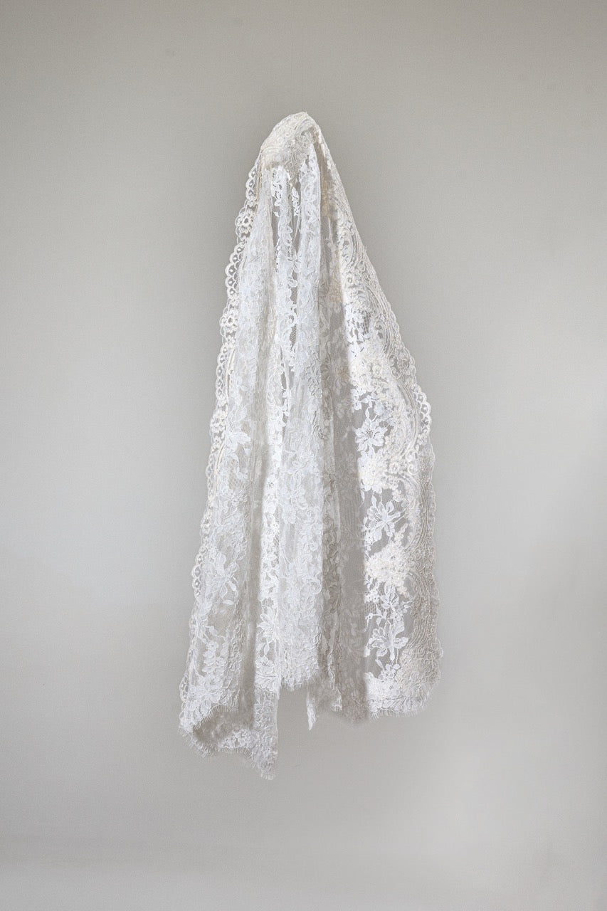 White lace veil hanging against a plain background