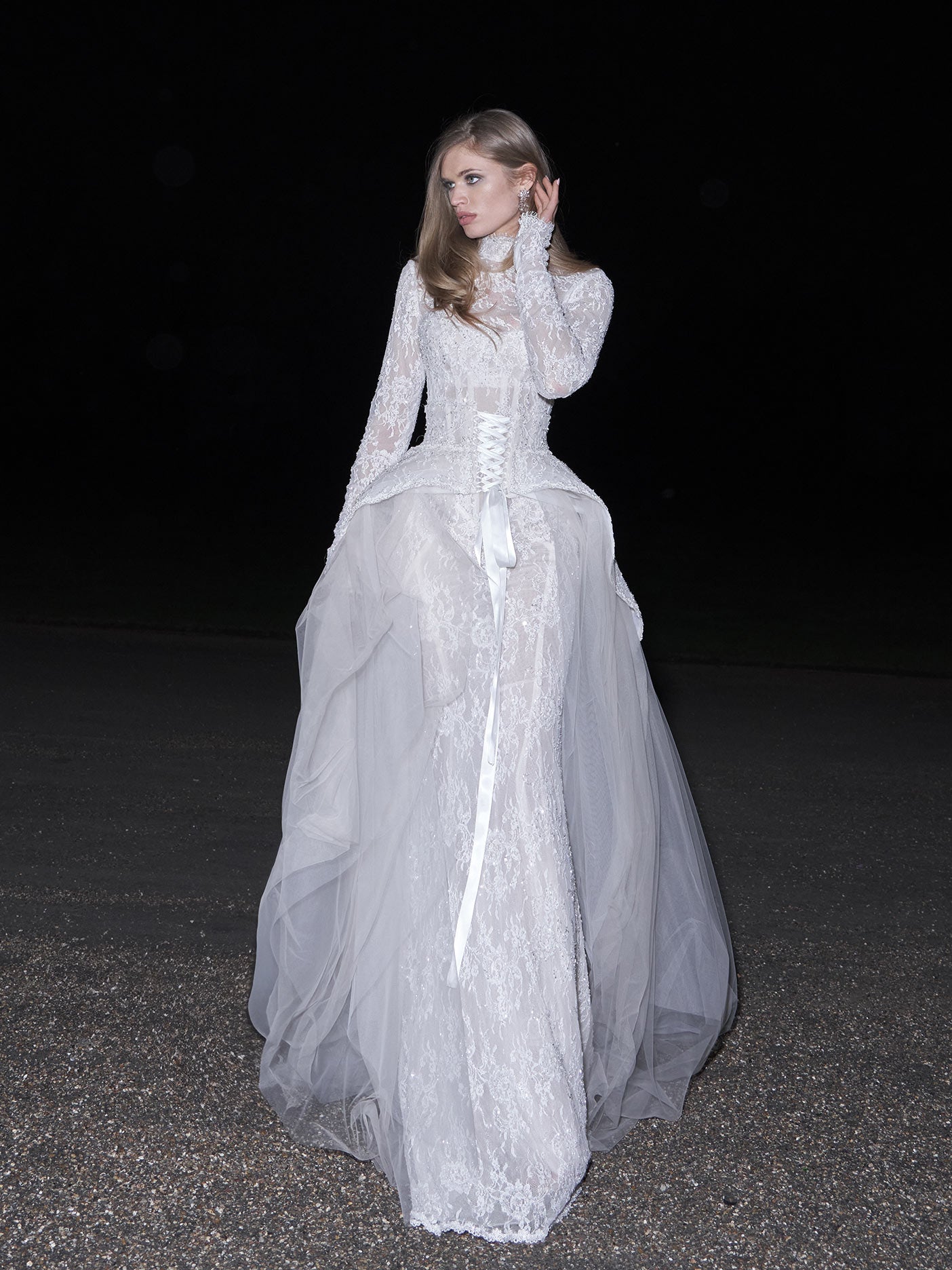 Woman wearing a white lace dress against a dark background