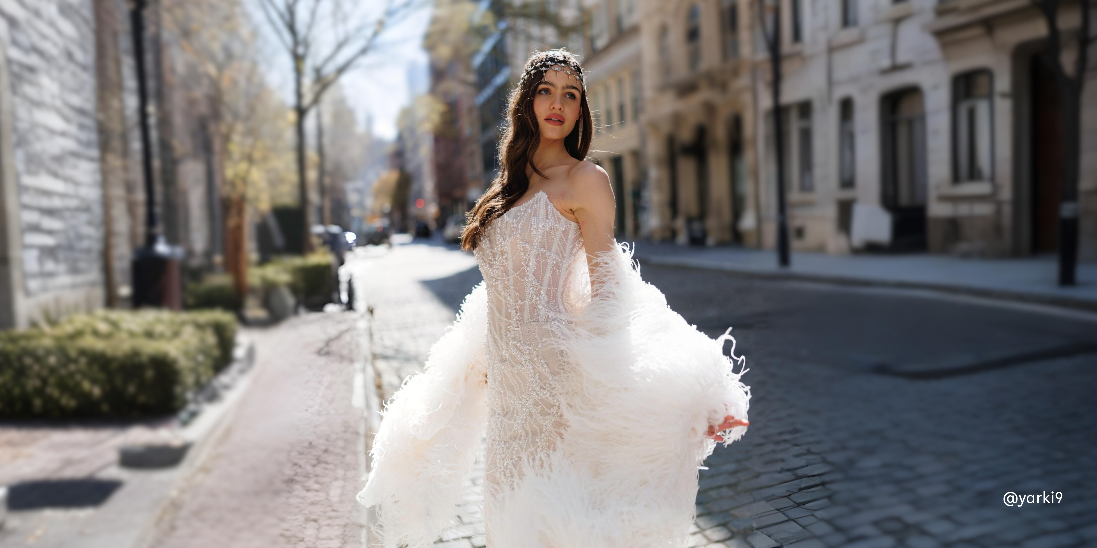 Woman in a white wedding dress standing on a street with buildings in the background