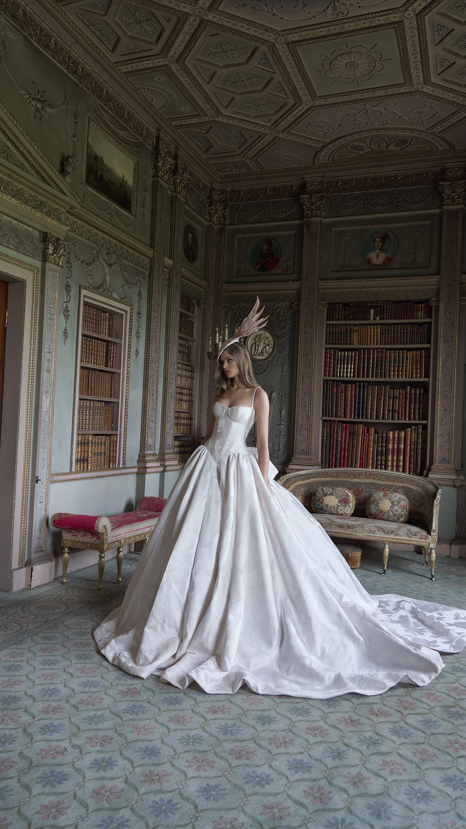 Woman in a white wedding dress standing in an ornate room with bookshelves and decorative elements.