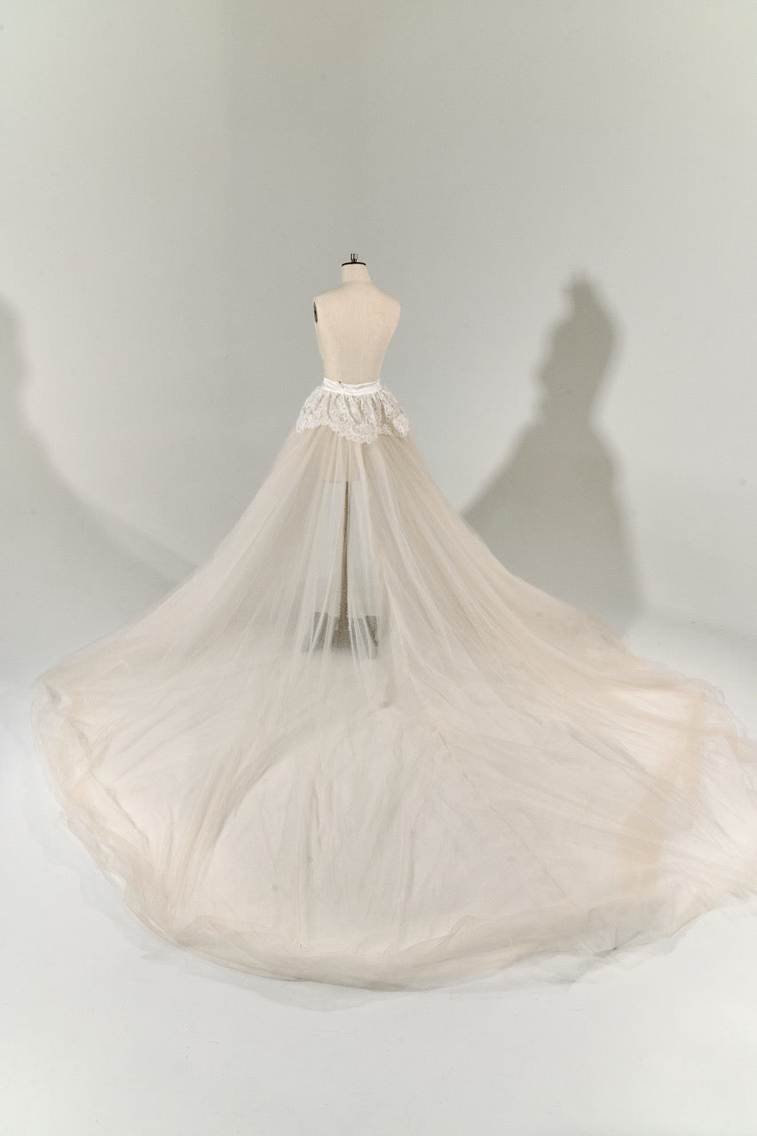 Mannequin wearing a long, flowing beige skirt against a plain background