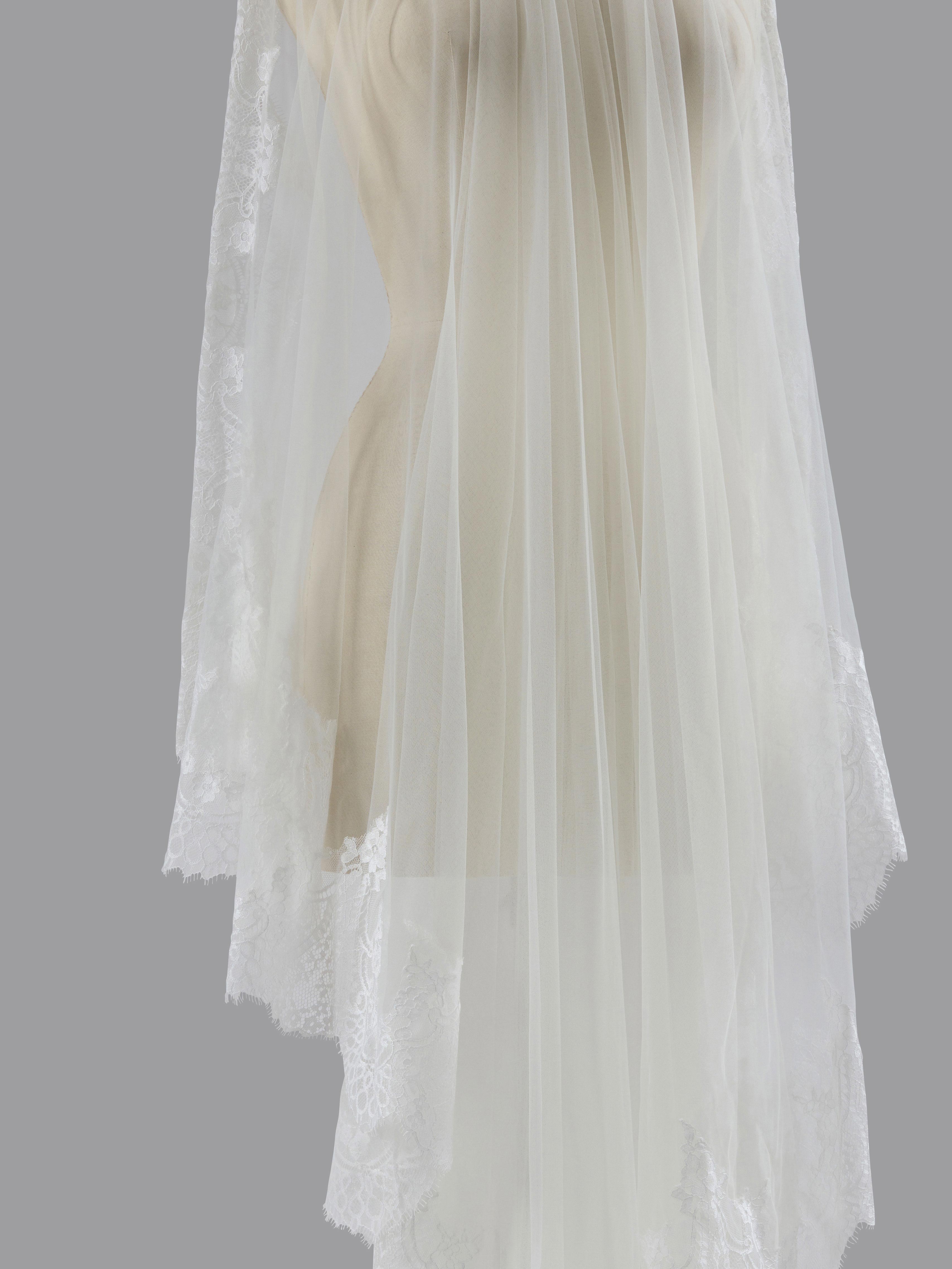 White lace dress with sheer overlay on a gray background