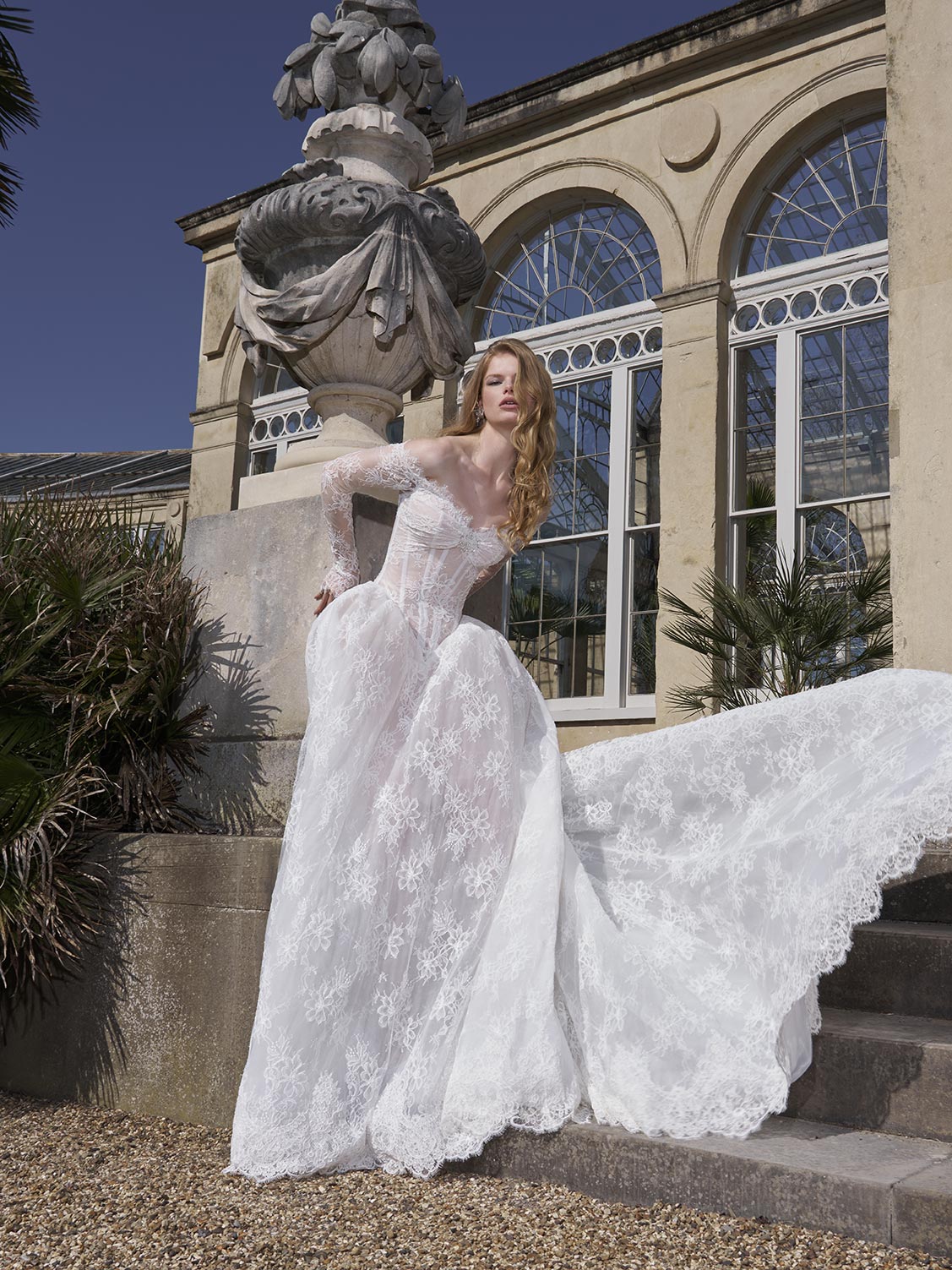 Woman in a white wedding dress standing on steps with a classical building in the background
